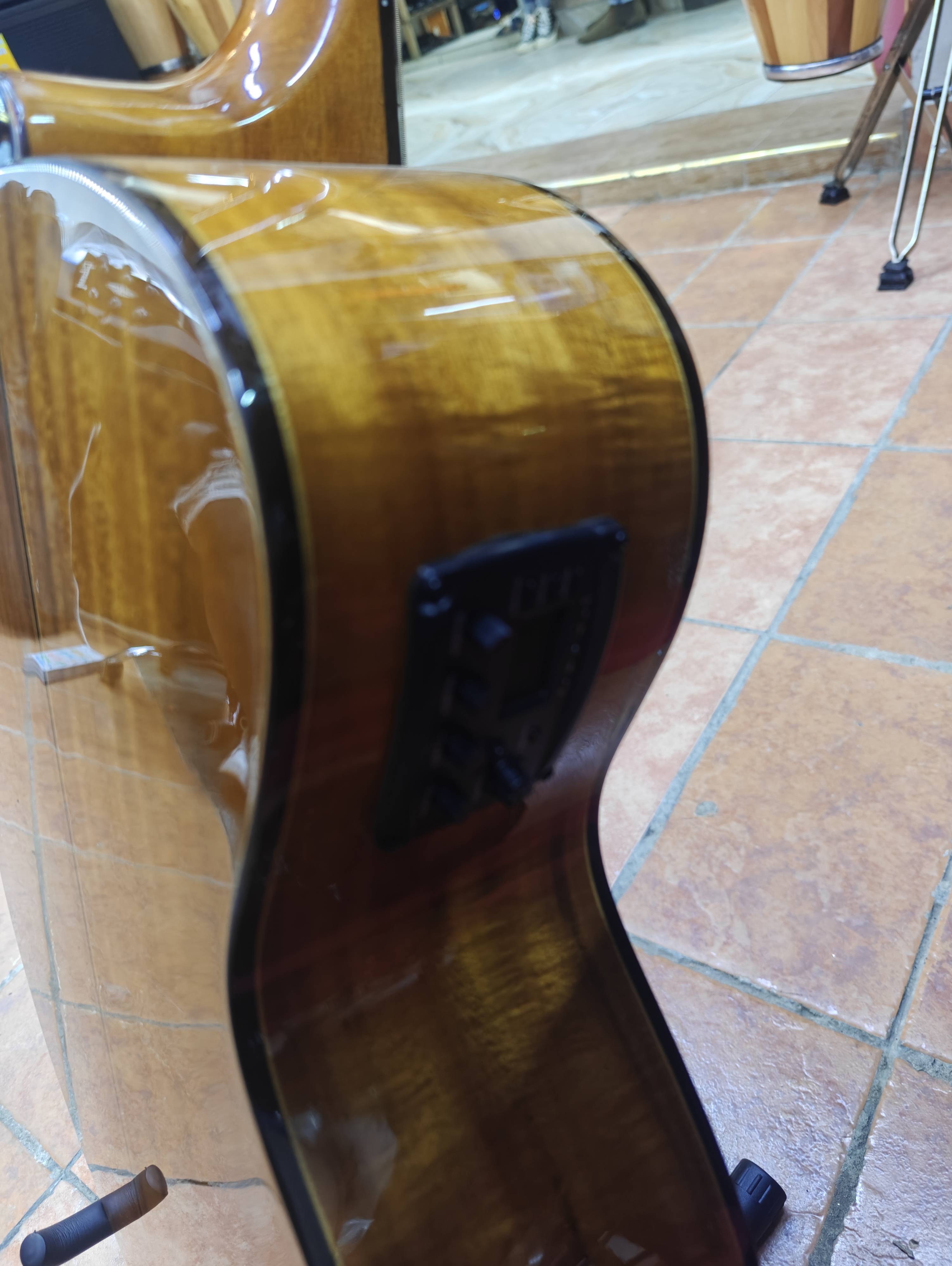 Side profile of the Spread Music semi-acoustic guitar showing the built-in EQ preamp, tuner, and figured wood sides.