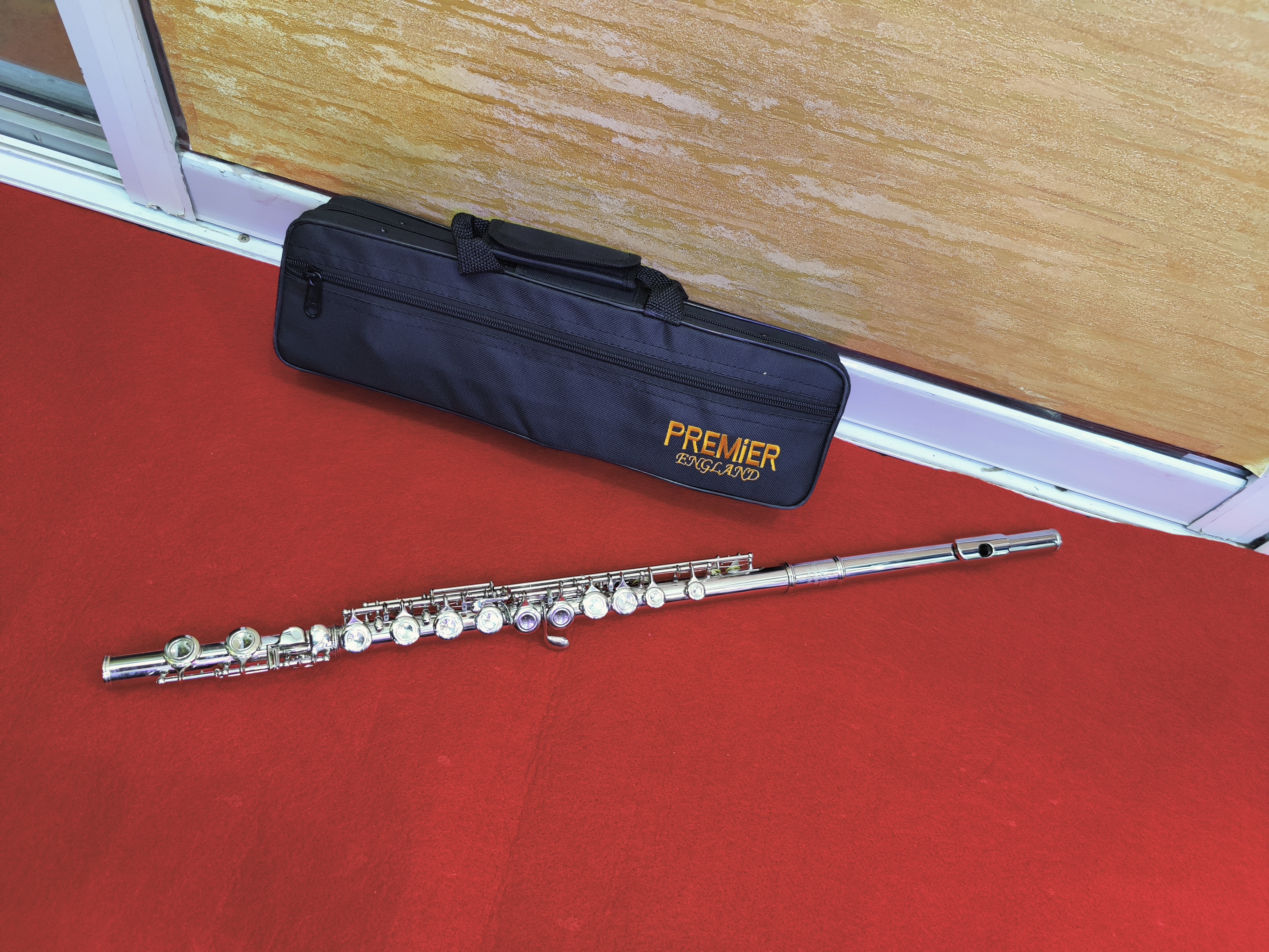 Premier silver-plated C concert flute with precision keys, protective case, and cleaning accessories for students and professional musicians.